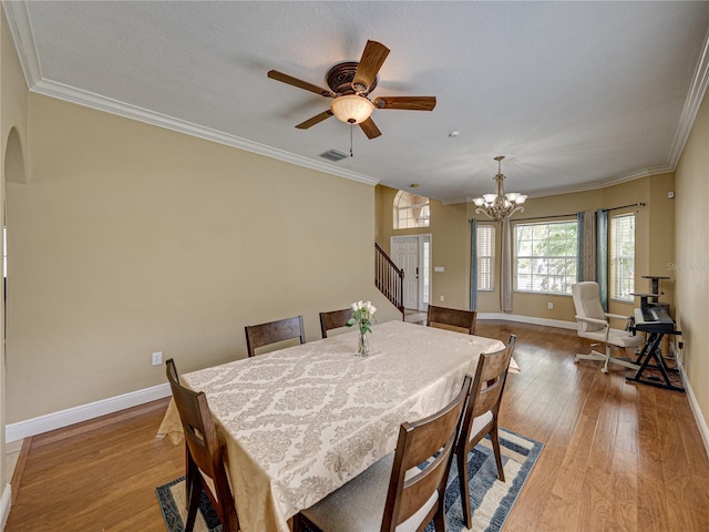 dining room featuring crown molding, wood-type flooring, baseboards, and arched walkways