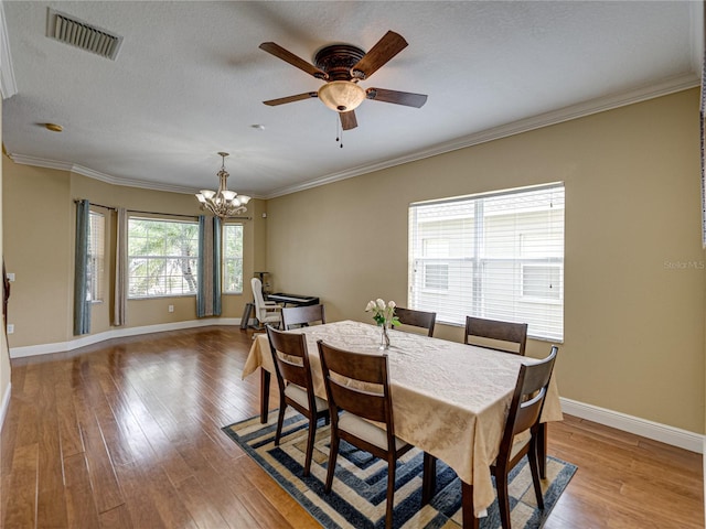 dining area featuring baseboards, ornamental molding, light wood-style floors, visible vents, and ceiling fan with notable chandelier