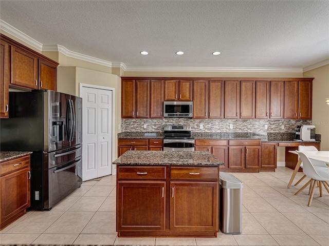 kitchen with dark stone countertops, a center island, stainless steel appliances, decorative backsplash, and light tile patterned flooring
