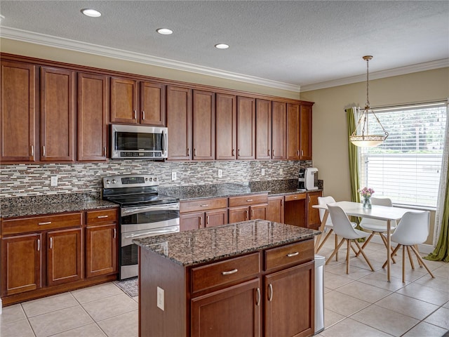 kitchen with stainless steel appliances, brown cabinetry, crown molding, and light tile patterned flooring