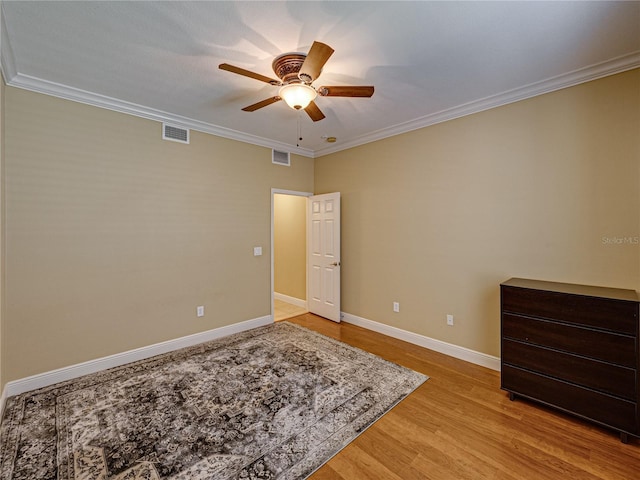 unfurnished bedroom featuring ornamental molding, visible vents, baseboards, and light wood-style floors
