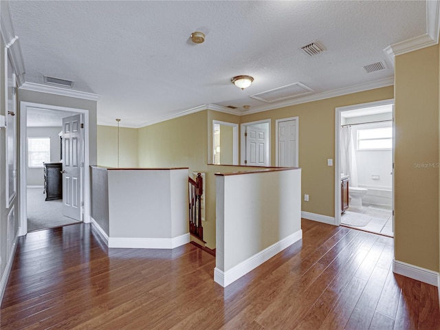 empty room with ornamental molding, visible vents, and hardwood / wood-style flooring