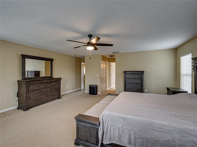 carpeted bedroom with a textured ceiling, baseboards, a ceiling fan, and visible vents