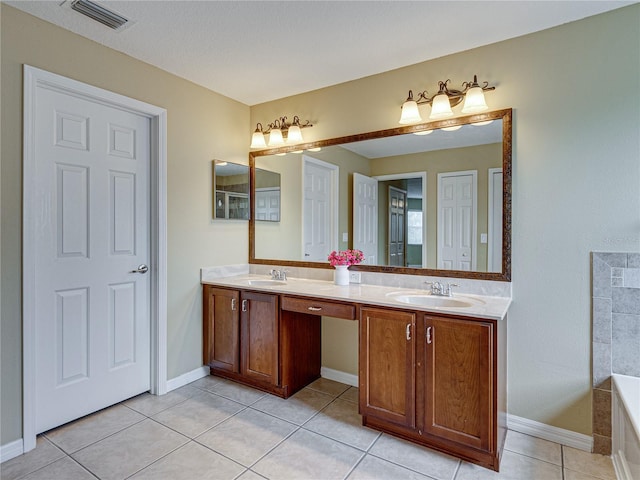 bathroom with a bathing tub, a sink, tile patterned flooring, and visible vents