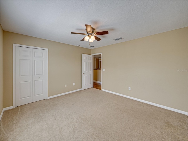 unfurnished bedroom featuring a closet, baseboards, a textured ceiling, visible vents, and carpet