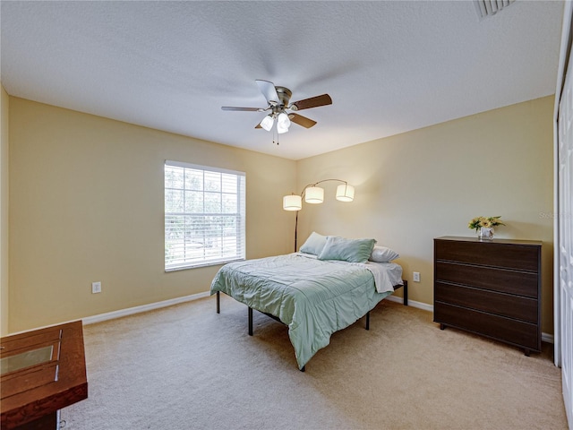 bedroom featuring baseboards, ceiling fan, light carpet, and a textured ceiling