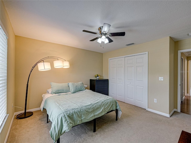 carpeted bedroom featuring visible vents, baseboards, a ceiling fan, and a closet