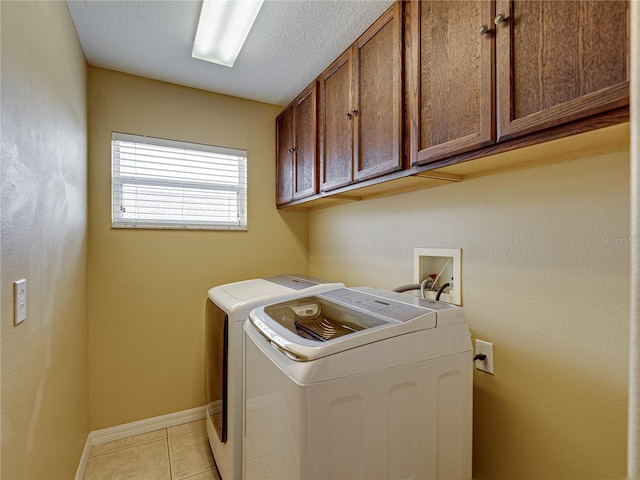 laundry area featuring light tile patterned floors, baseboards, a textured ceiling, cabinet space, and washing machine and clothes dryer