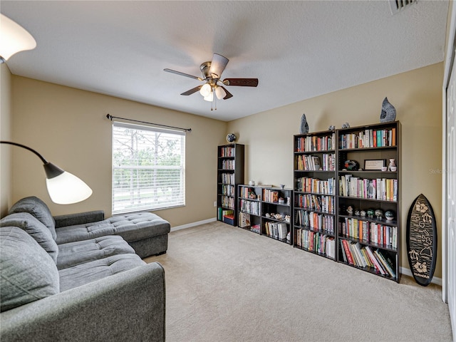 living area featuring baseboards, carpet flooring, a textured ceiling, a ceiling fan, and visible vents