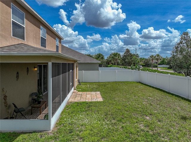 view of yard featuring a patio, a fenced backyard, and a sunroom