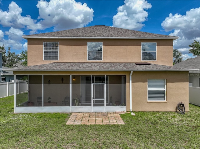 back of house featuring a sunroom, a lawn, and stucco siding