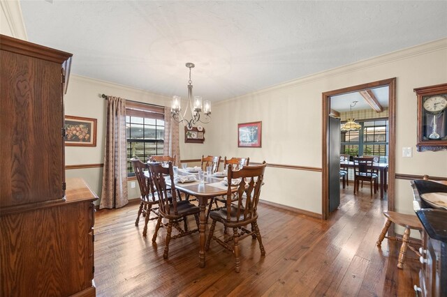 dining space featuring crown molding, baseboards, hardwood / wood-style floors, and a notable chandelier