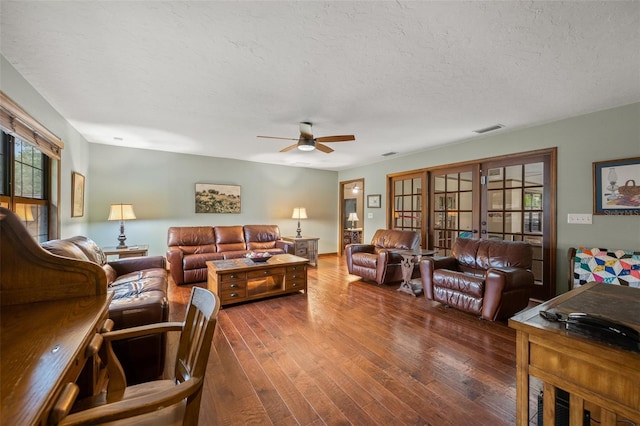 living room featuring a textured ceiling, wood-type flooring, a ceiling fan, and plenty of natural light