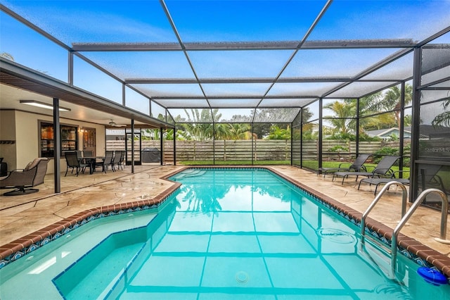 outdoor pool with a patio area, glass enclosure, and fence