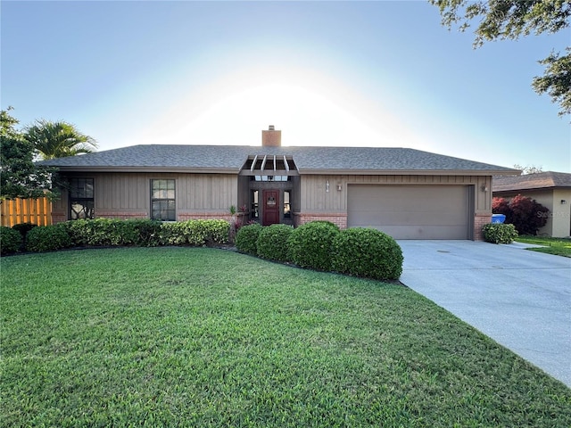 view of front of house featuring concrete driveway, a chimney, a front yard, brick siding, and a garage