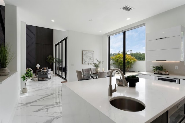 7608 Antilla St, Tampa, FL 33625 - kitchen with marble finish floor, modern cabinets, light stone counters, and visible vents