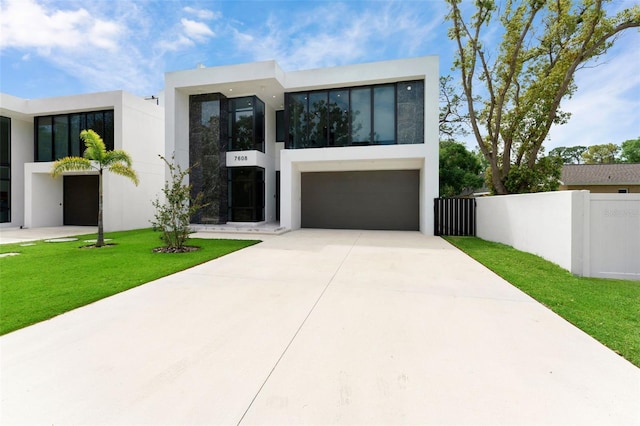 7608 Antilla St, Tampa, FL 33625 - contemporary home with driveway, stucco siding, an attached garage, fence, and a front lawn