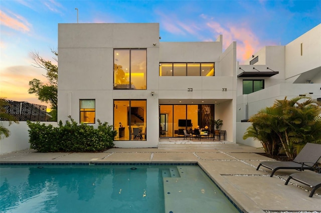 7608 Antilla St, Tampa, FL 33625 - back of property at dusk featuring a fenced in pool, stucco siding, and a patio