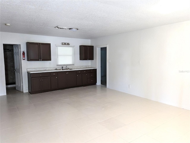 kitchen with dark brown cabinets, visible vents, light countertops, and a textured ceiling