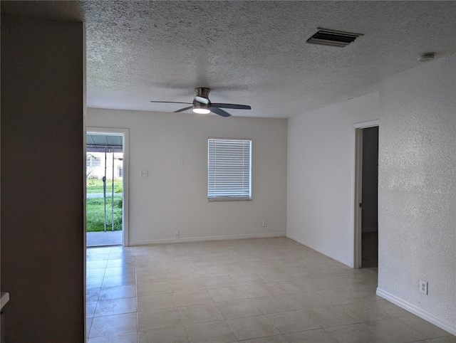 empty room featuring a textured ceiling, a ceiling fan, visible vents, a textured wall, and baseboards