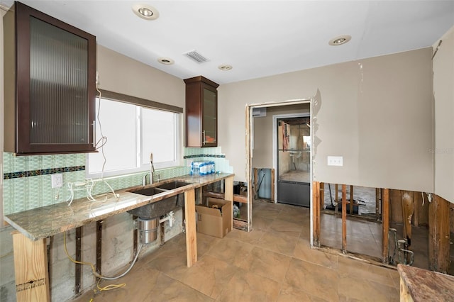 366 La Hacienda Dr, Indian Rocks Beach, FL 33785 - kitchen with decorative backsplash, visible vents, dark brown cabinets, a sink, and glass insert cabinets