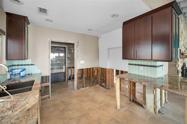 366 La Hacienda Dr, Indian Rocks Beach, FL 33785 - kitchen with visible vents, tasteful backsplash, light stone countertops, dark brown cabinets, and a sink