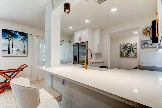 2488 Del Rio Way, Dunedin, FL 34698 - kitchen featuring stainless steel refrigerator with ice dispenser, a kitchen breakfast bar, a sink, white cabinetry, and light countertops