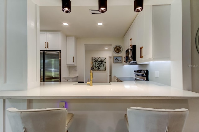 2488 Del Rio Way, Dunedin, FL 34698 - kitchen with appliances with stainless steel finishes, a peninsula, white cabinets, recessed lighting, and a sink