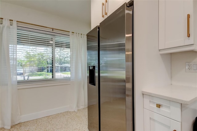 2488 Del Rio Way, Dunedin, FL 34698 - kitchen featuring stainless steel refrigerator with ice dispenser, speckled floor, white cabinets, light countertops, and baseboards