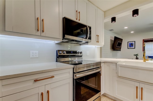 2488 Del Rio Way, Dunedin, FL 34698 - kitchen with stainless steel appliances, light countertops, white cabinetry, and recessed lighting