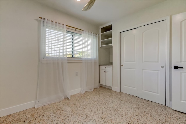 2488 Del Rio Way, Dunedin, FL 34698 - unfurnished bedroom featuring dark aggregate flooring, a closet, baseboards, and a ceiling fan