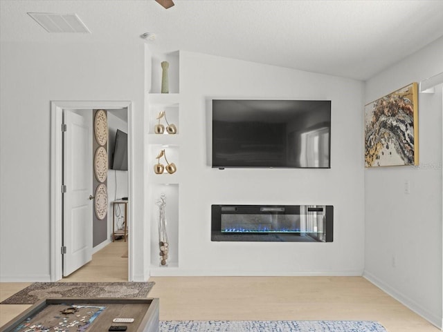 9617 Branching Ship Trce, Wesley Chapel, FL 33545 - unfurnished living room with baseboards, a glass covered fireplace, wood finished floors, and visible vents
