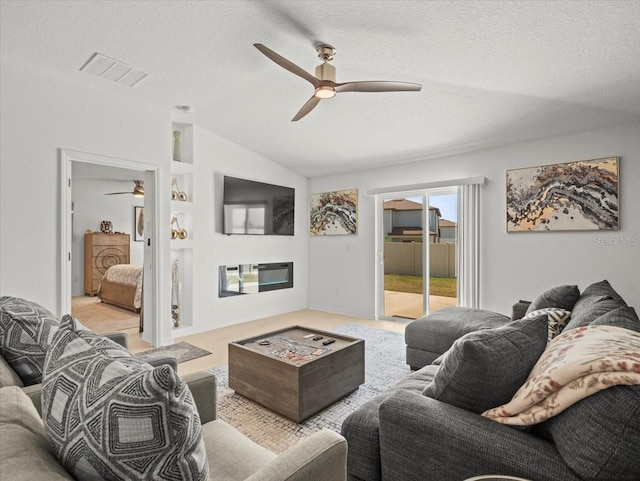 9617 Branching Ship Trce, Wesley Chapel, FL 33545 - living area with vaulted ceiling, a ceiling fan, a textured ceiling, a glass covered fireplace, and visible vents