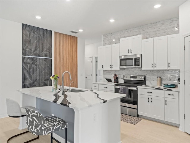 9617 Branching Ship Trce, Wesley Chapel, FL 33545 - kitchen with white cabinets, stainless steel appliances, visible vents, a sink, and light wood-style flooring