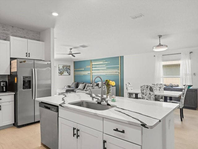 9617 Branching Ship Trce, Wesley Chapel, FL 33545 - kitchen featuring white cabinets, a kitchen island with sink, light wood-style flooring, a sink, and appliances with stainless steel finishes