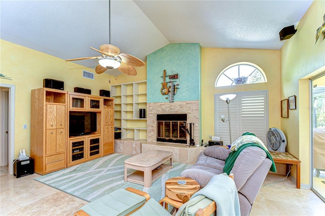 14119 Stonegate Dr, Tampa, FL 33624 - living area featuring a textured ceiling, high vaulted ceiling, visible vents, a tiled fireplace, and a ceiling fan