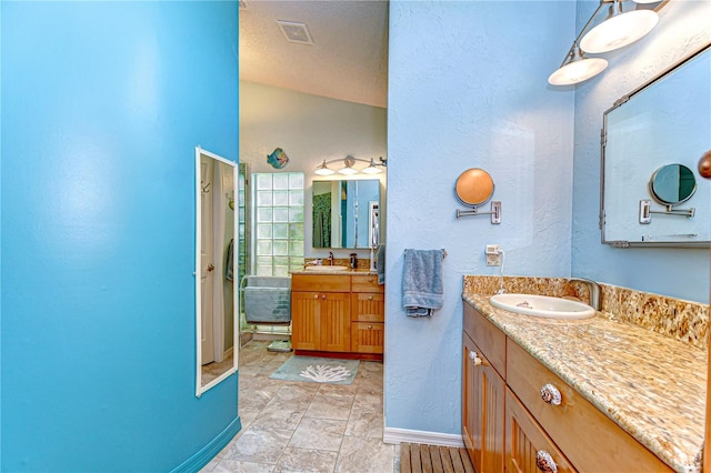 14119 Stonegate Dr, Tampa, FL 33624 - full bathroom with a textured wall, baseboards, a sink, visible vents, and two vanities
