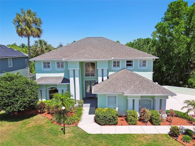 mediterranean / spanish-style house featuring stucco siding, a shingled roof, and a front yard