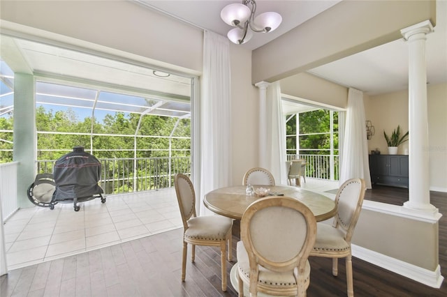 dining space featuring baseboards, decorative columns, wood finished floors, and a notable chandelier