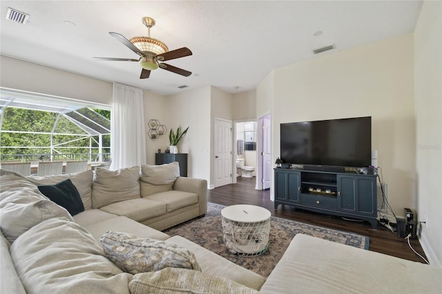 living room featuring baseboards, a ceiling fan, dark wood-type flooring, and visible vents