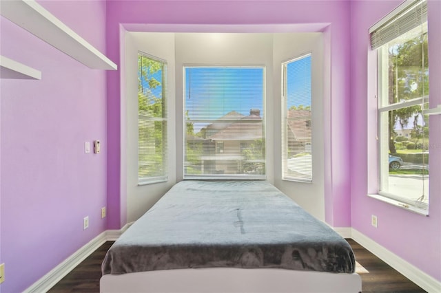 bedroom with multiple windows, baseboards, and dark wood finished floors