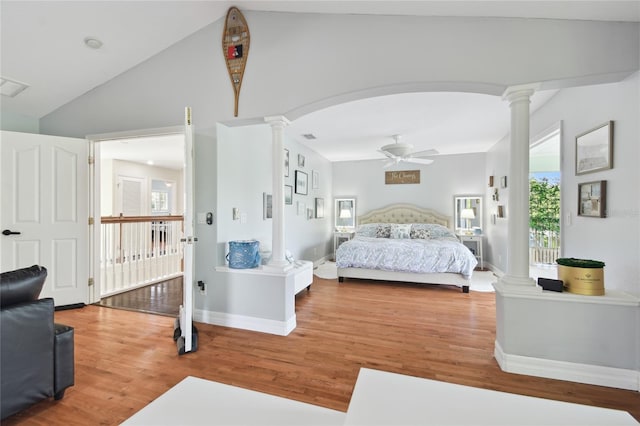 bedroom with lofted ceiling, wood finished floors, arched walkways, baseboards, and decorative columns