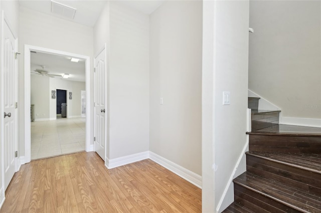 staircase with wood finished floors, visible vents, a ceiling fan, and baseboards