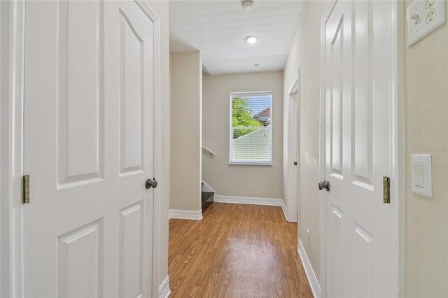 hall with light wood-type flooring and baseboards