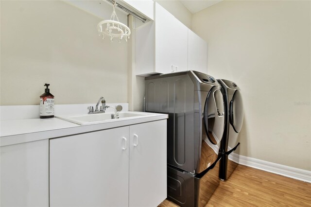washroom with a sink, baseboards, light wood-style floors, independent washer and dryer, and cabinet space