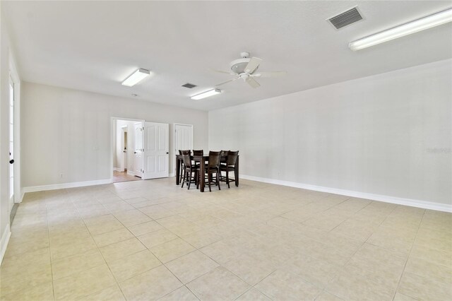 unfurnished room with light tile patterned floors, baseboards, visible vents, and ceiling fan