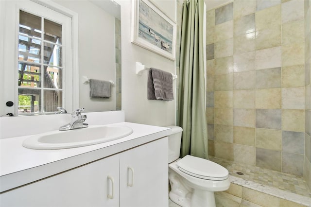 full bathroom featuring a tile shower, toilet, and vanity
