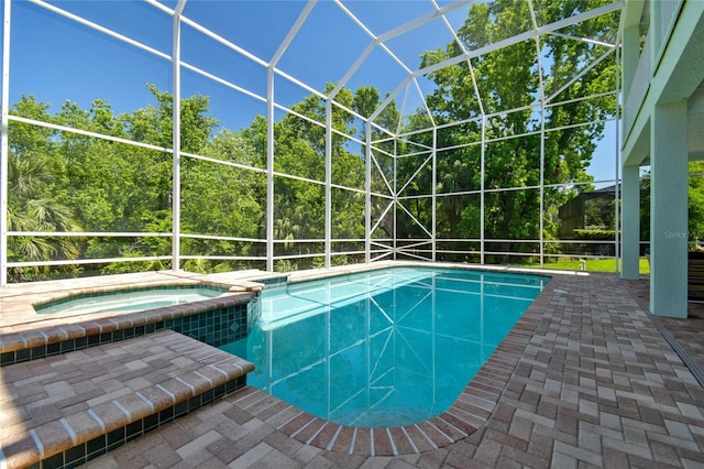 view of swimming pool featuring glass enclosure, a pool with connected hot tub, and a patio