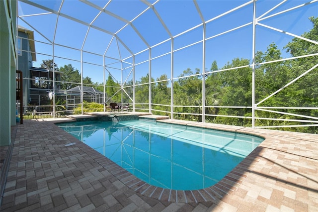 view of pool with a patio, glass enclosure, and a pool with connected hot tub