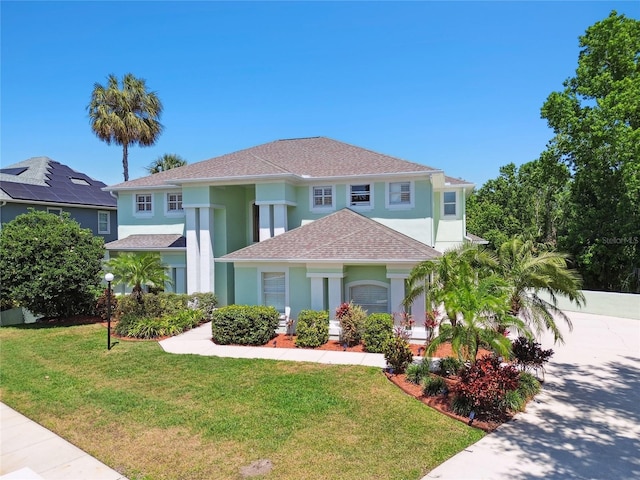 mediterranean / spanish-style home featuring a shingled roof, a front lawn, and stucco siding